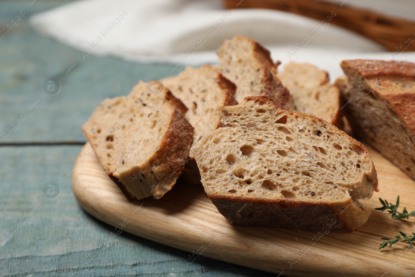 Photo of Cut buckwheat baguette with thyme on light blue wooden table, closeup