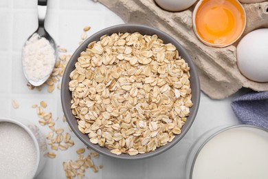 Photo of Different ingredients for cooking tasty oatmeal pancakes on white tiled table, flat lay
