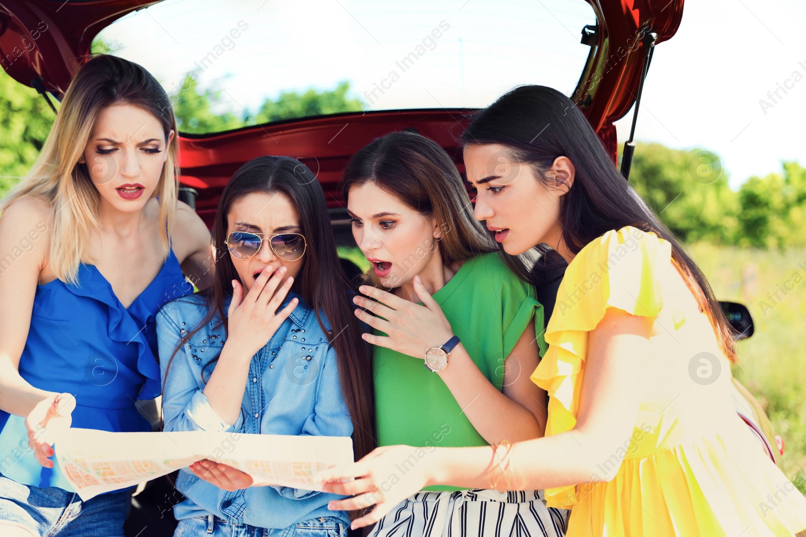 Photo of Beautiful young women with map near car