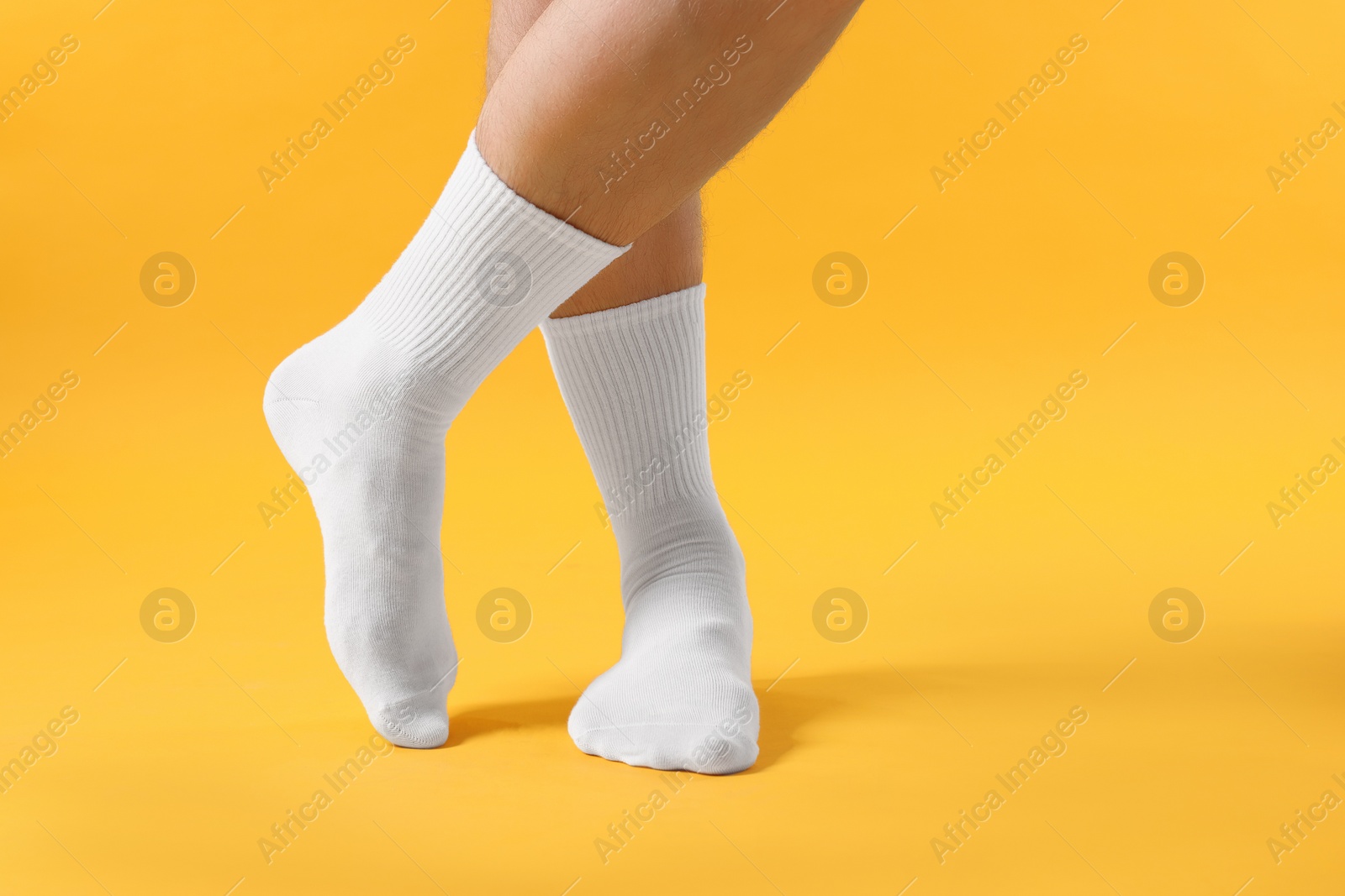 Photo of Man in stylish white socks on yellow background, closeup.Space for text