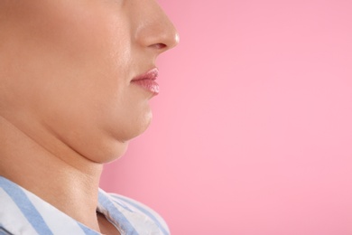 Photo of Young woman with double chin on pink background, closeup. Space for text