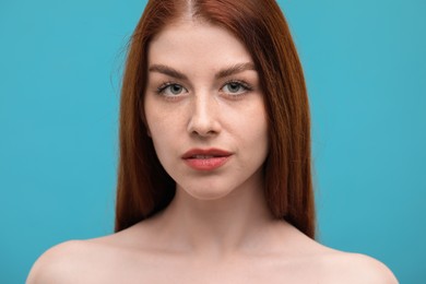 Portrait of beautiful woman with freckles on light blue background