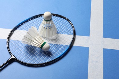 Photo of Feather badminton shuttlecocks and racket on blue background. Space for text