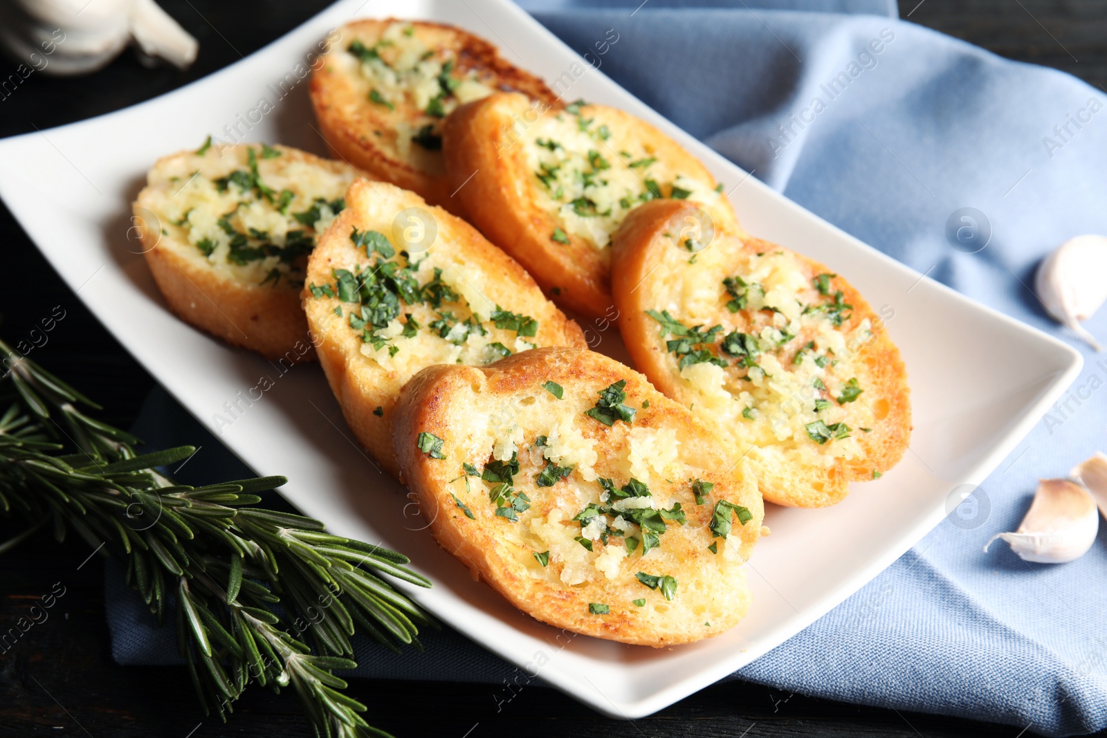 Photo of Plate with delicious homemade garlic bread on table