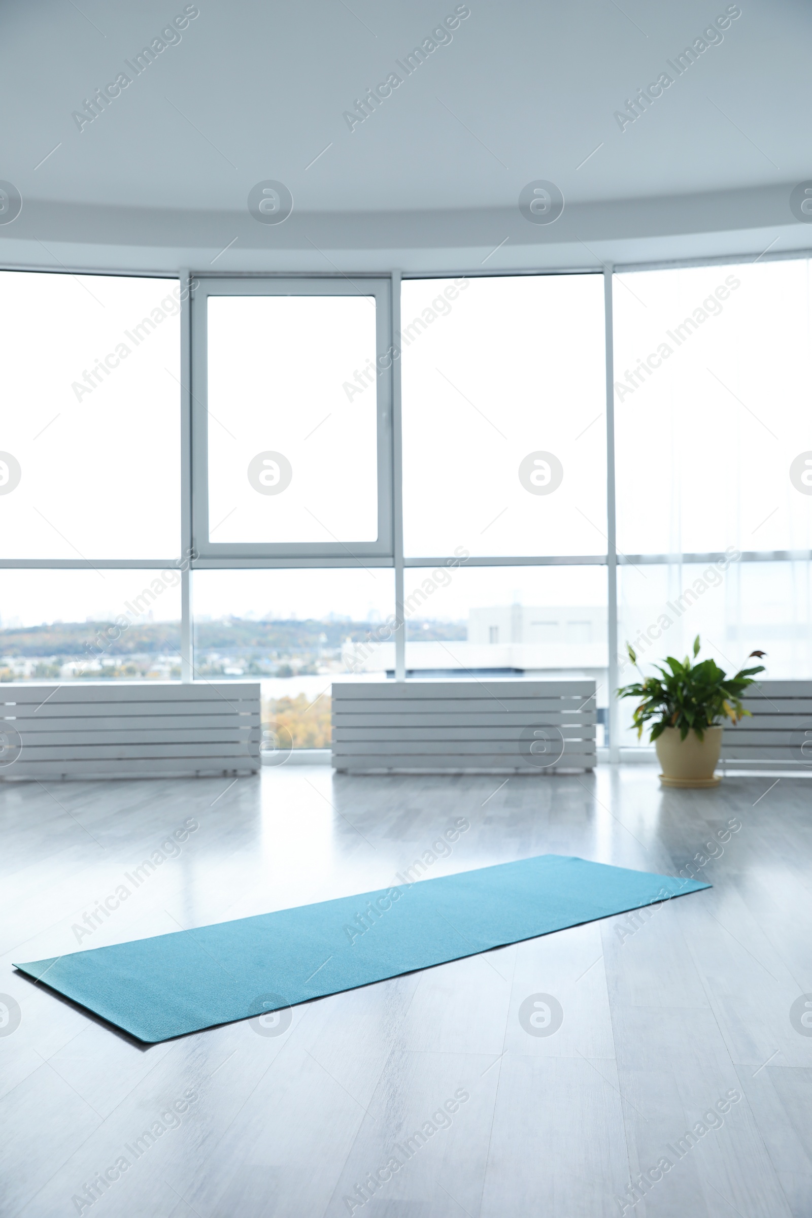 Photo of Unrolled light blue yoga mat on floor in room