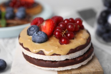 Photo of Crunchy rice cakes with peanut butter and sweet berries on table, closeup