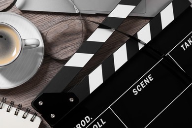 Photo of Movie clapper, film reel and coffee on wooden table, flat lay