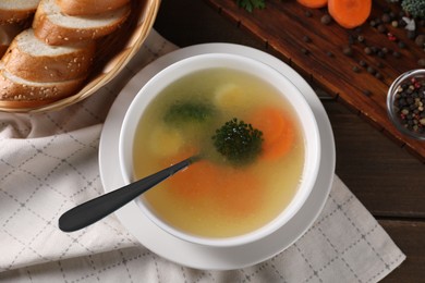 Photo of Tasty soup with vegetables in bowl served on wooden table, flat lay