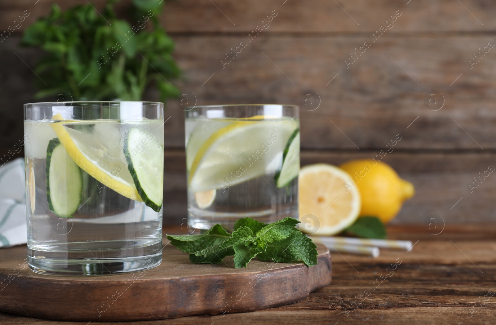 Photo of Refreshing water with cucumber, lemon and mint on wooden table. Space for text