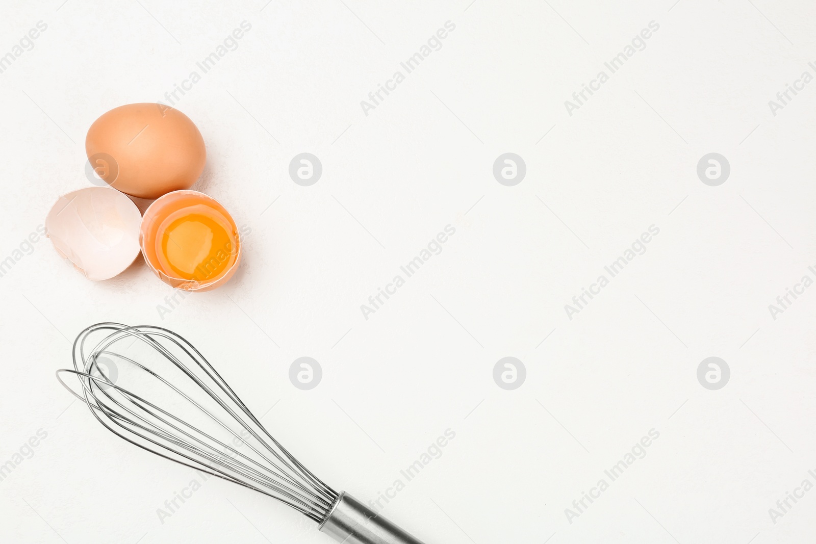 Photo of Raw eggs and whisk on white table, top view with space for text. Baking pie