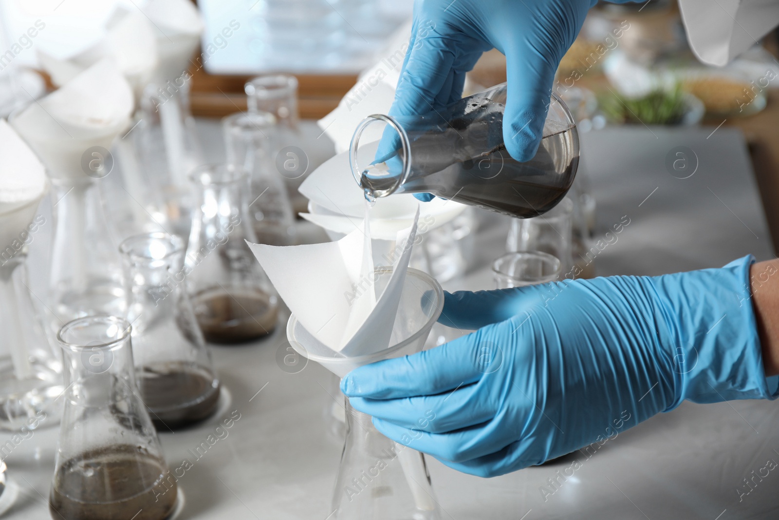 Photo of Scientist filtering soil samples at table, closeup. Laboratory analysis