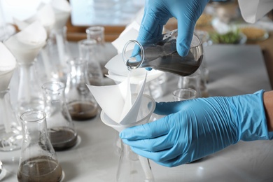 Photo of Scientist filtering soil samples at table, closeup. Laboratory analysis