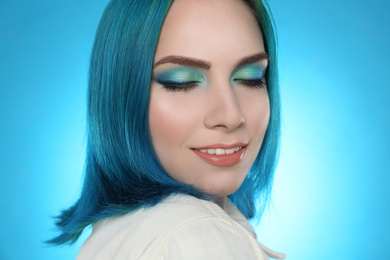 Photo of Young woman with bright dyed hair on light blue background, closeup