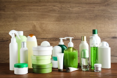 Photo of Different body care products on table against wooden background