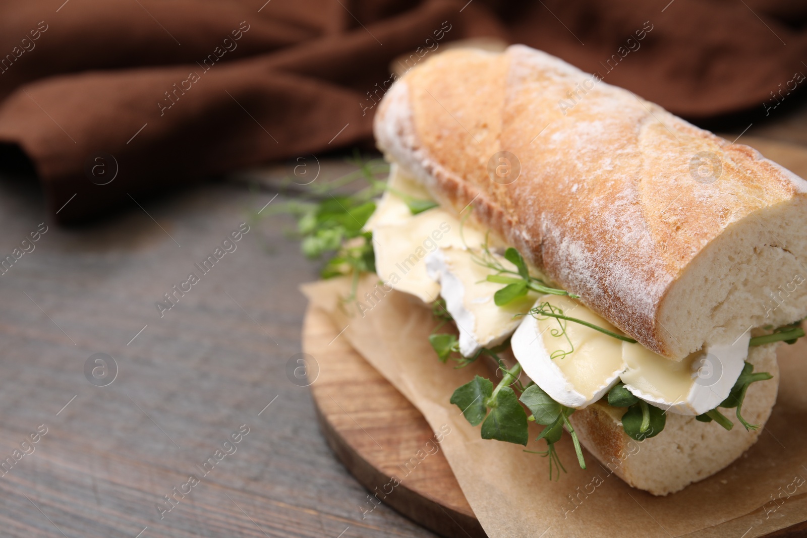 Photo of Tasty sandwich with brie cheese on wooden table, closeup. Space for text