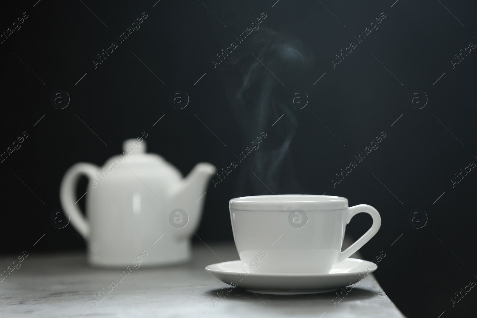 Photo of Cup of tea and saucer on table against dark background