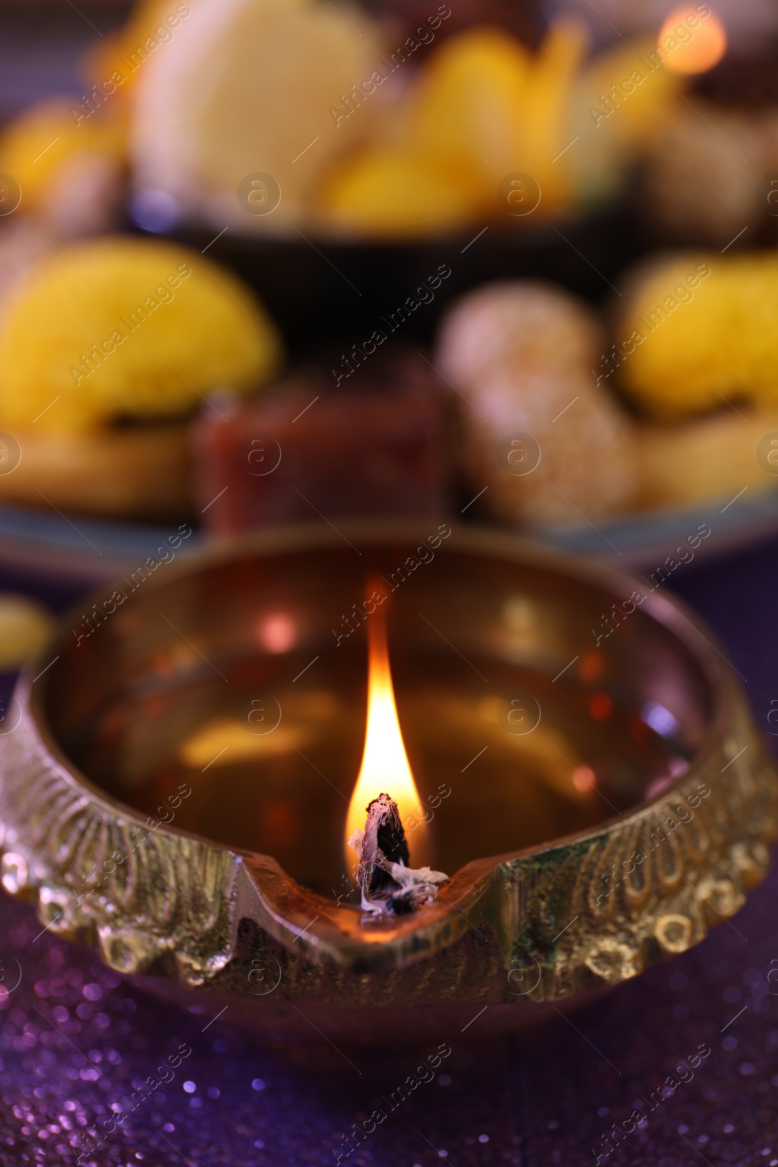 Photo of Diwali celebration. Diya lamp on shiny violet table, closeup