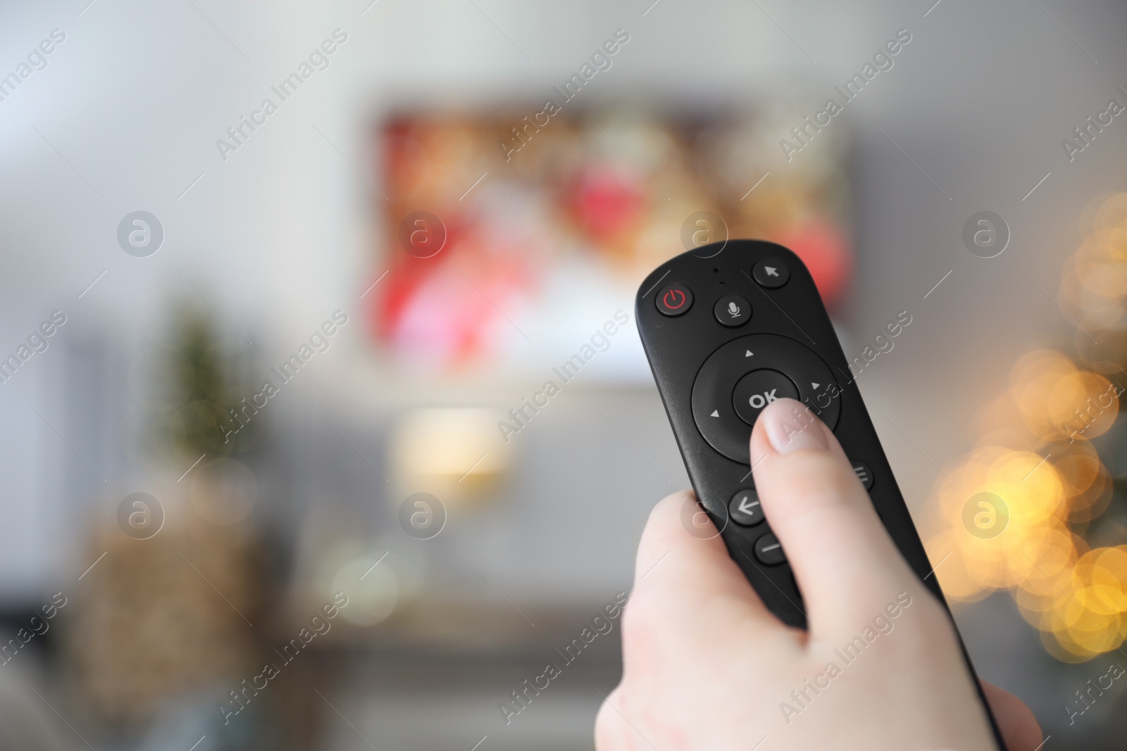 Photo of Woman with remote control in room decorated for Christmas, closeup