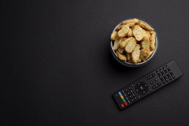 Photo of Modern tv remote control and rusks on black background, flat lay. Space for text
