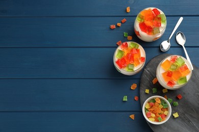 Photo of Delicious broken glass jelly dessert on blue wooden table, flat lay. Space for text