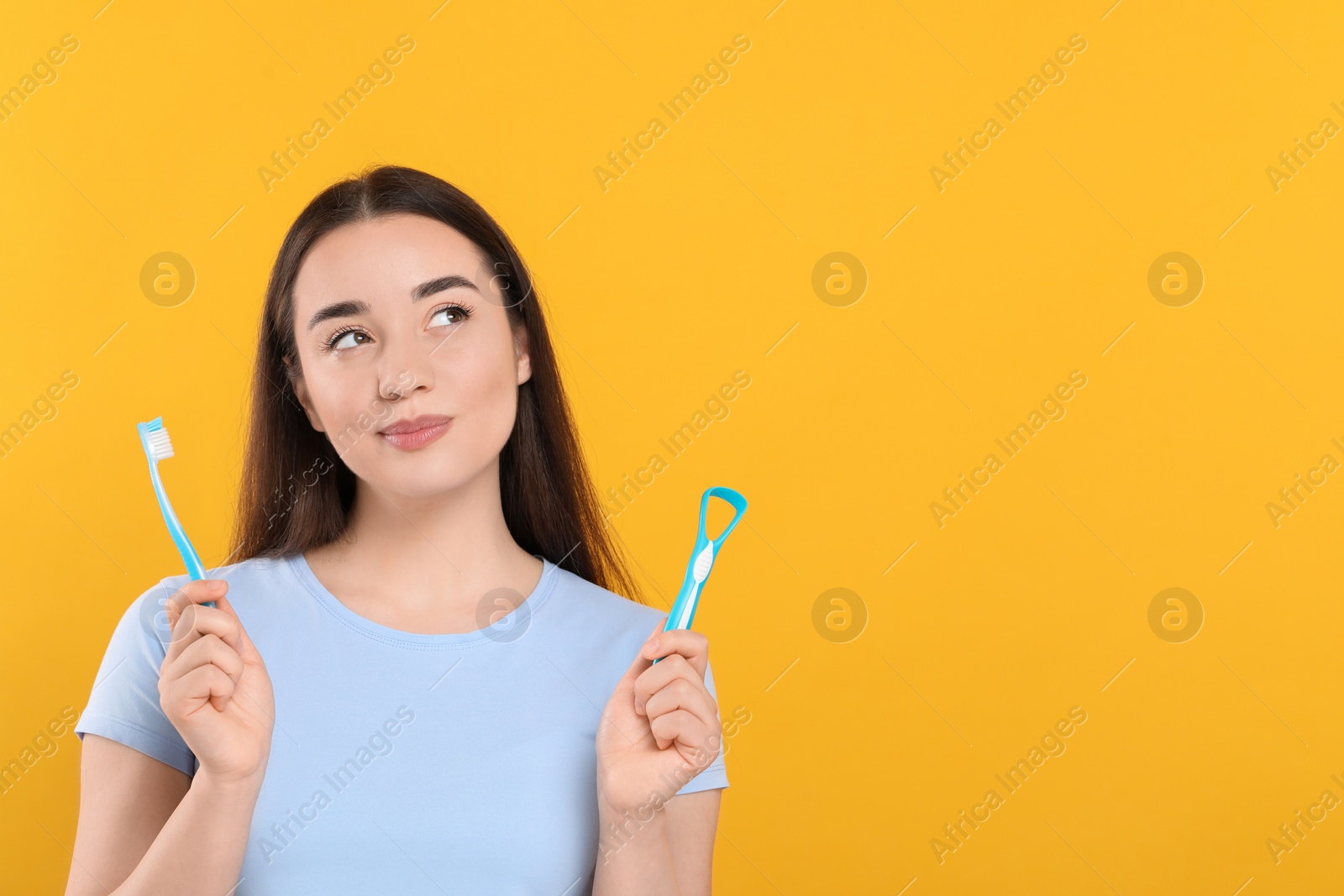 Photo of Beautiful woman with tongue cleaner and plastic toothbrush on yellow background, space for text