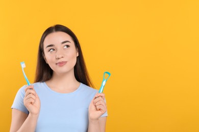 Photo of Beautiful woman with tongue cleaner and plastic toothbrush on yellow background, space for text