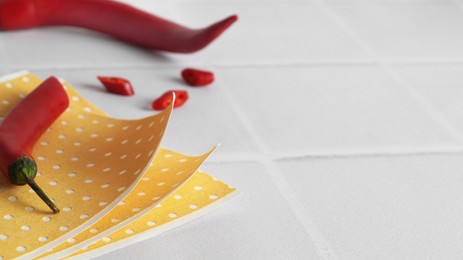 Photo of Pepper plasters and chili on white tiled table, closeup. Space for text