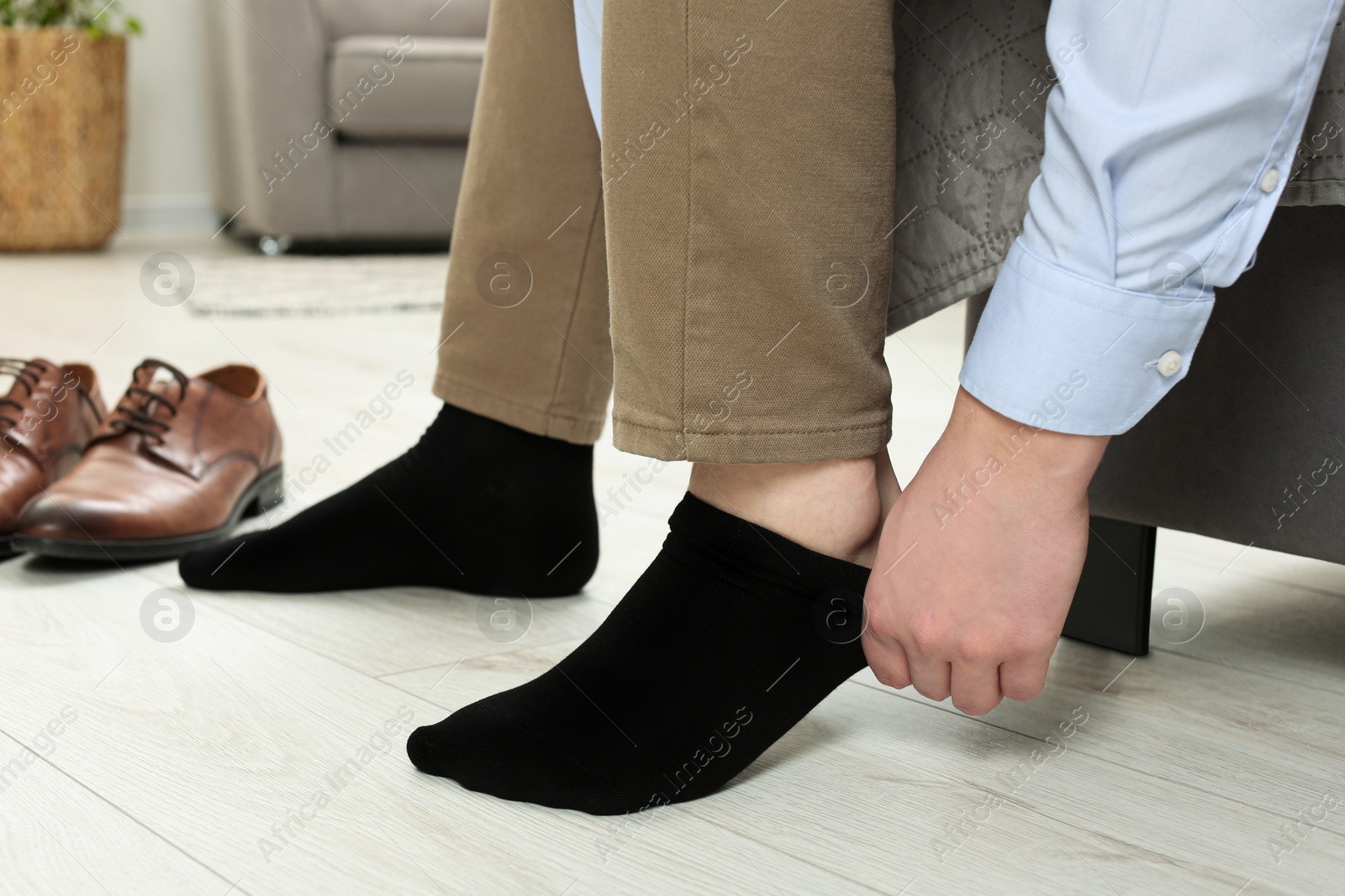 Photo of Man putting on black socks at home, closeup