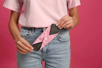 Photo of Young woman with reusable menstrual pad on bright pink background, closeup