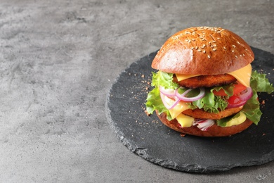 Photo of Slate plate with double vegetarian burger on grey background. Space for text