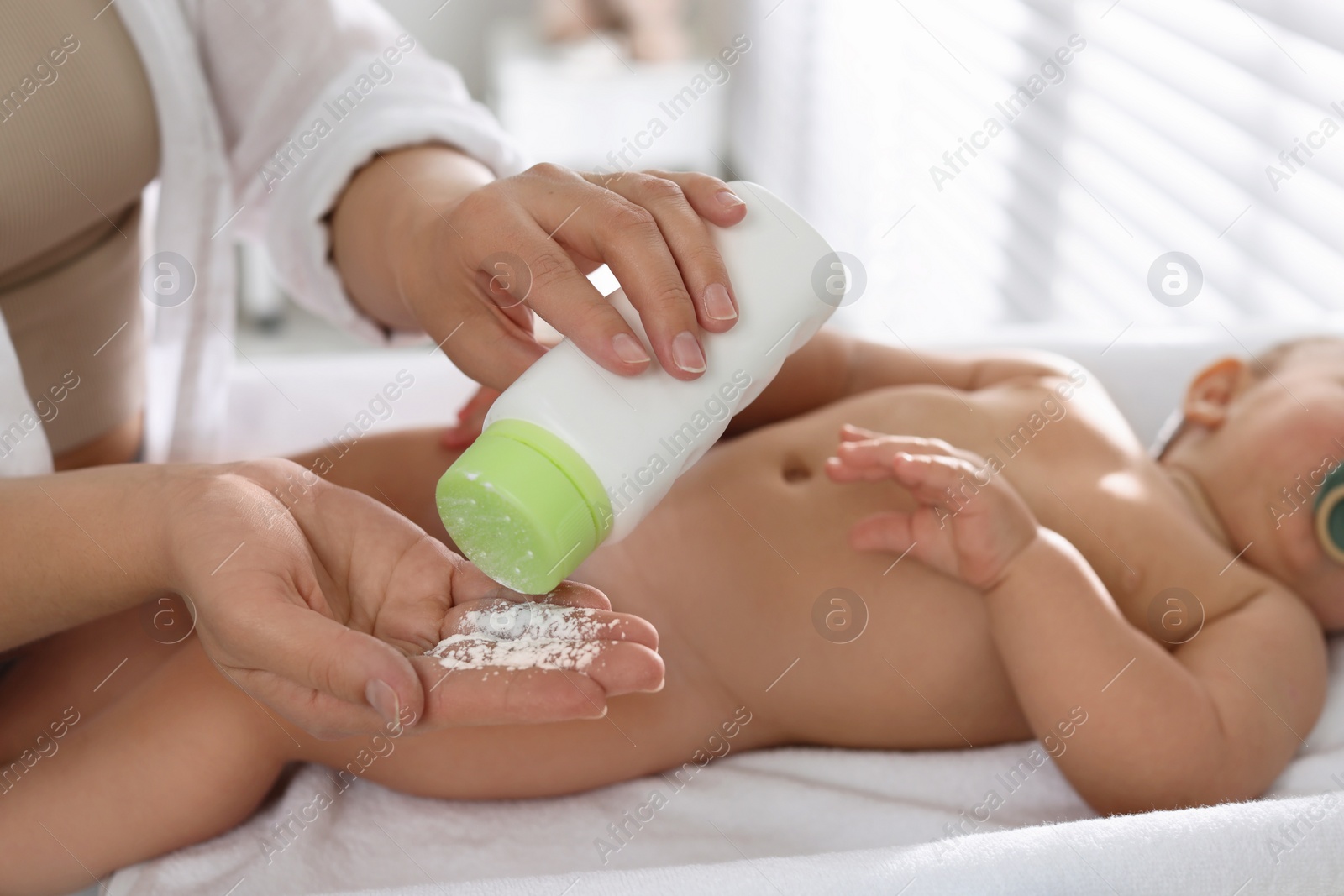 Photo of Mother with dusting powder near her baby at home, closeup