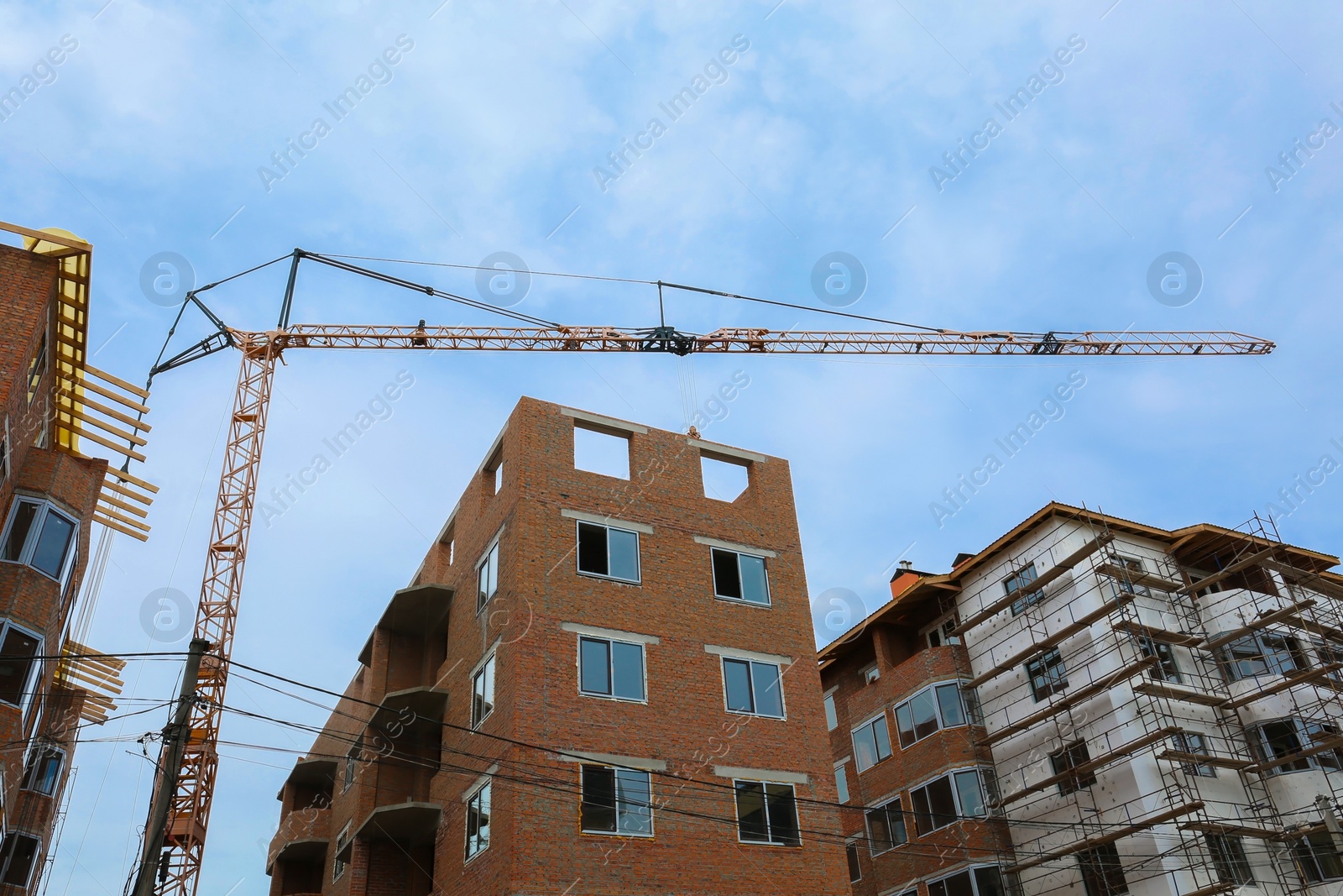 Photo of Construction site with tower crane near unfinished buildings, low angle view