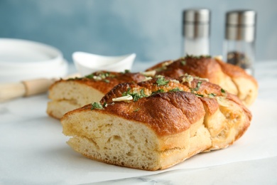 Photo of Delicious homemade garlic bread with herbs on table