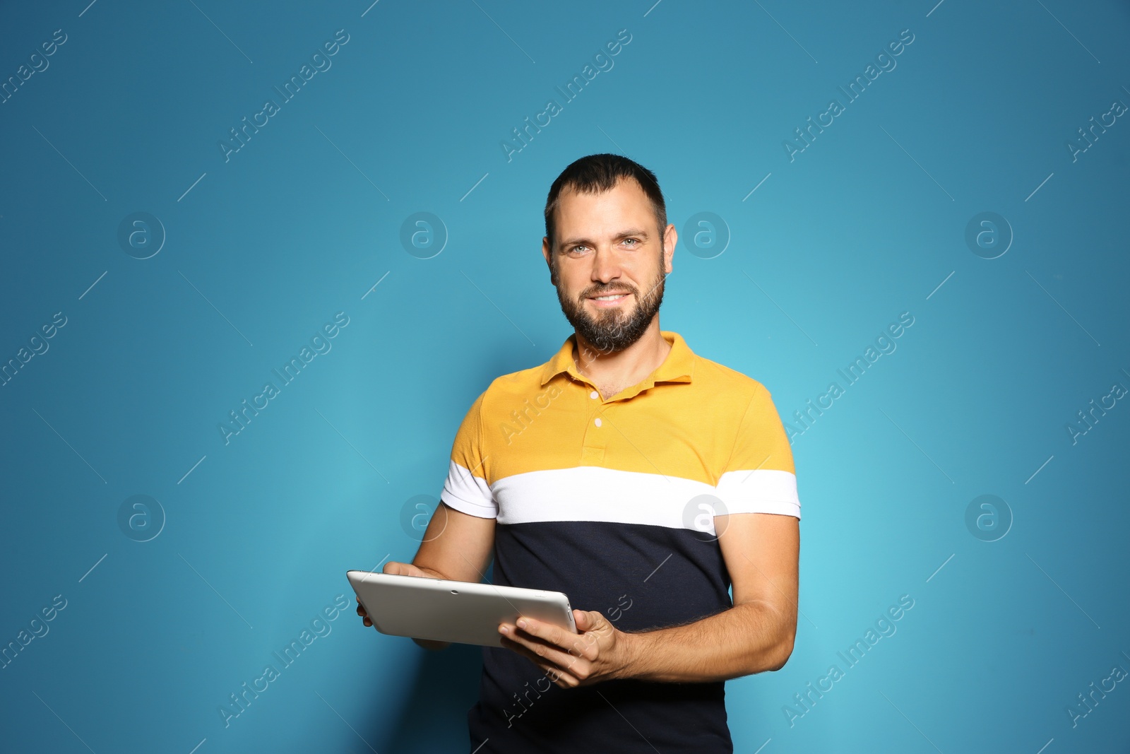 Photo of Man in casual clothes with tablet on color background