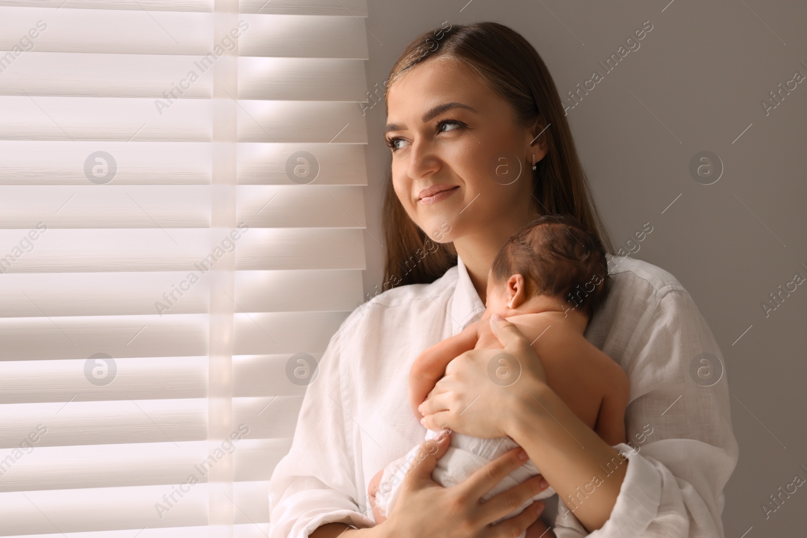 Photo of Mother holding her cute newborn baby indoors