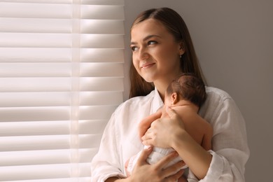 Mother holding her cute newborn baby indoors