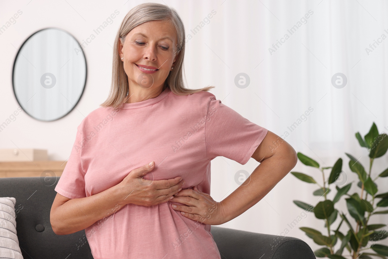 Photo of Beautiful senior woman doing breast self-examination at home