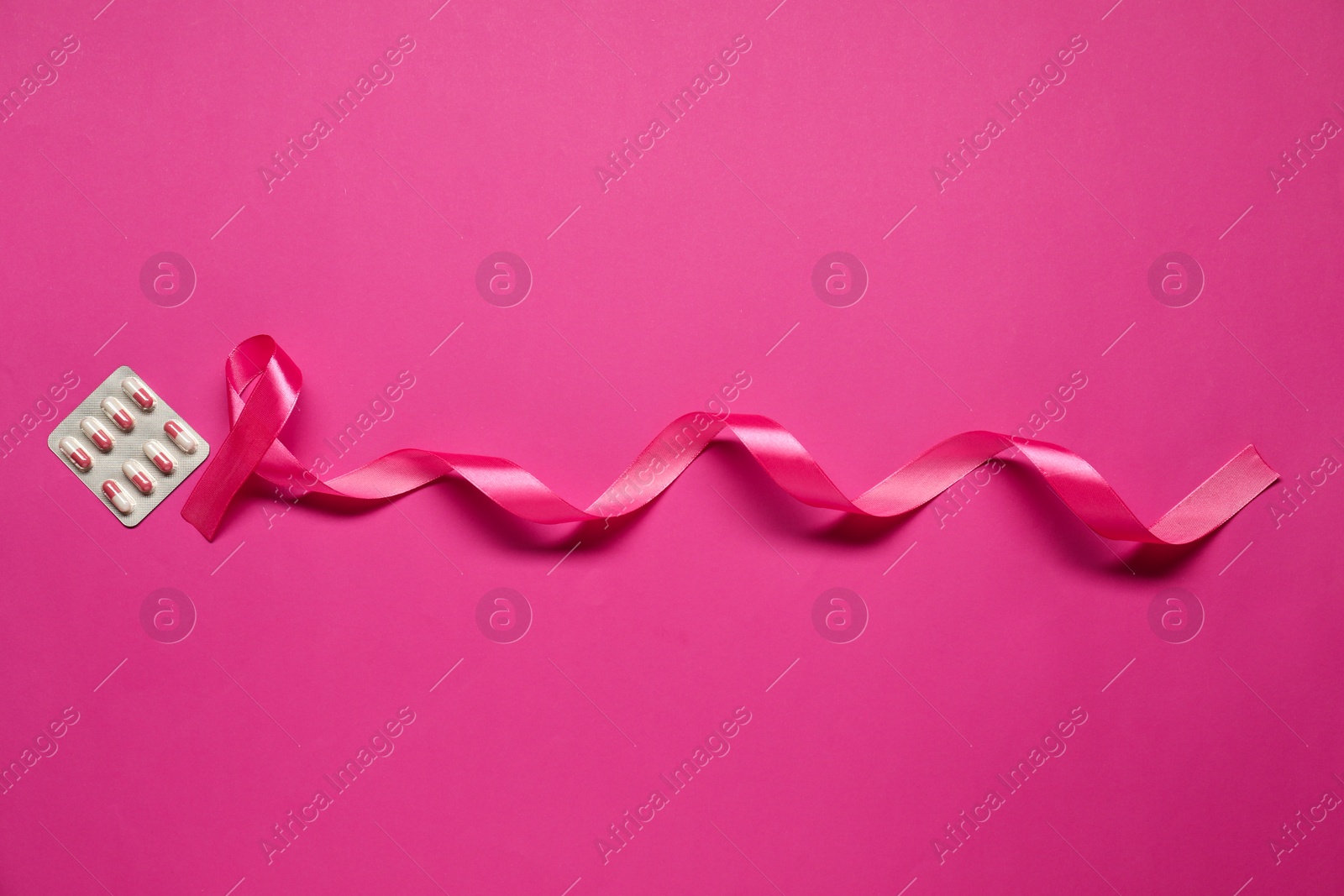 Photo of Pink ribbon on color background, flat lay. Breast cancer awareness