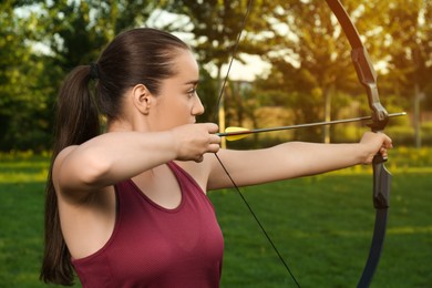 Photo of Woman with bow and arrow practicing archery in park