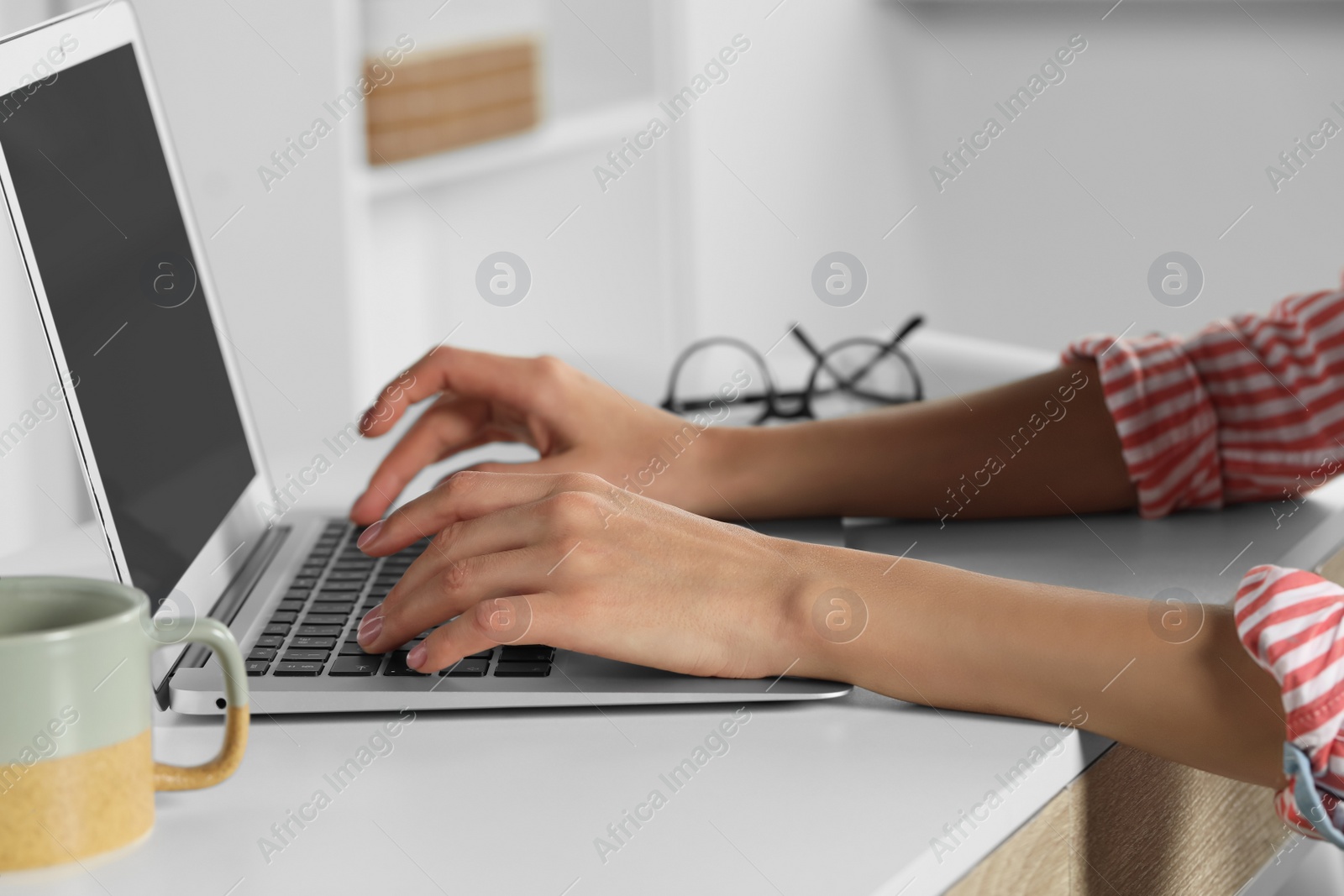 Photo of Young woman working with laptop at workplace indoors, closeup