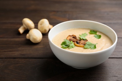 Photo of Bowl of fresh homemade mushroom soup on wooden table