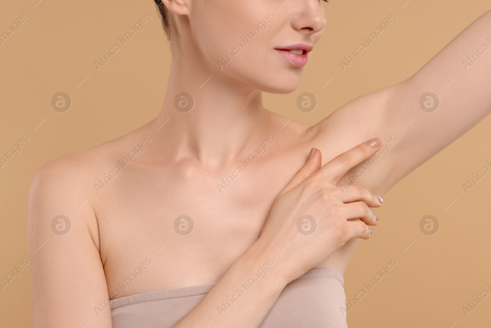 Photo of Woman showing armpit with smooth clean skin on beige background, closeup