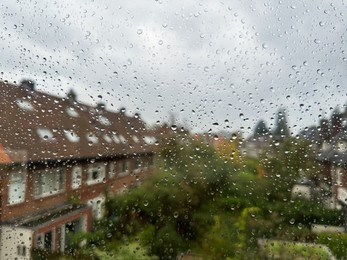 Photo of View on city street through window with water droplets on rainy day, closeup