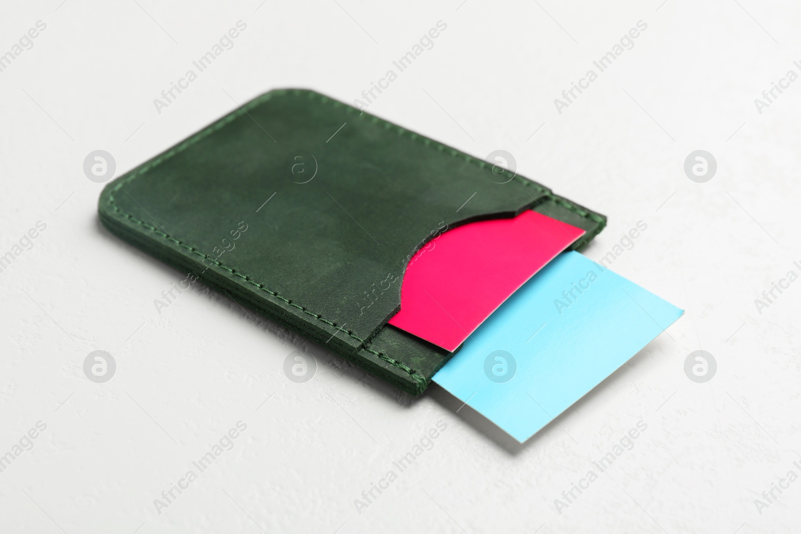 Photo of Leather business card holder with colorful cards on white table, closeup