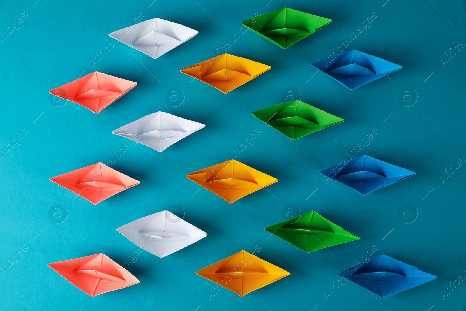 Photo of Many colorful handmade paper boats on light blue background, flat lay. Origami art