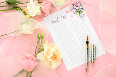 Photo of Guest list, pen, tulle fabric and beautiful flowers on pink background, flat lay. Space for text