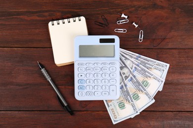 Photo of Calculator, notebook, pen, dollar banknotes and paper clips on wooden table, flat lay. Retirement concept
