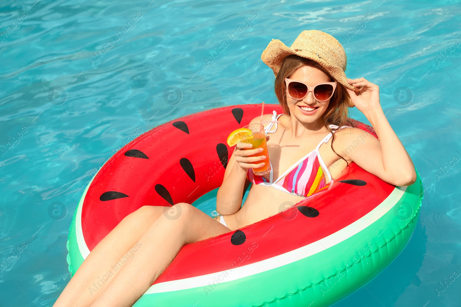 Photo of Young woman with cocktail in pool on sunny day