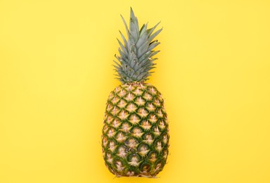 Delicious ripe pineapple on yellow background, top view