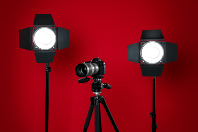 Photo of Professional video camera and lighting equipment on red background